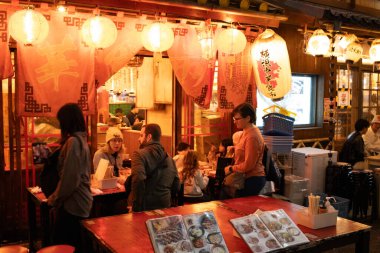 Tokyo, Japonya, 27 Ekim 2023: Müşteriler canlı bir Japon sokak yemekhanesinde yemek yiyor