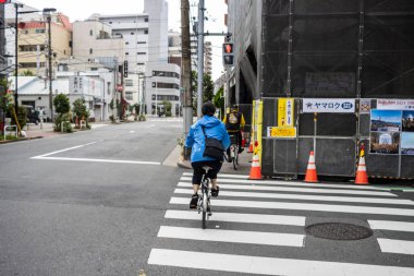 Tokyo, Japonya, 28 Ekim 2023: Teslimatçı Tokyo caddesinde bisiklet sürüyor