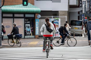 Tokyo, Japonya, 28 Ekim 2023: Bisikletçiler yeşil ışıkta karşıdan karşıya geçiyor