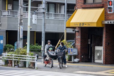 Tokyo, Japonya, 28 Ekim 2023: Tokyo kaldırımında bisiklet süren aile