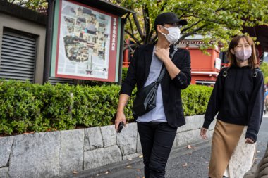 Tokyo, Japonya, 28 Ekim 2023: Maskeli çift şehir ortamında yürüyor