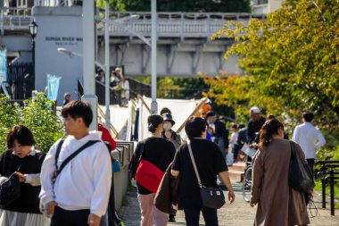 Tokyo, Japonya, 28 Ekim 2023: Güneşli bir günde Sumida Nehri boyunca yürüyen insanlar