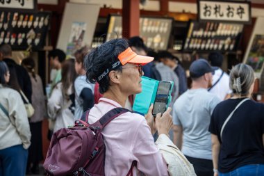 Tokyo, Japonya, 28 Ekim 2023: Senso-ji Tapınağı dükkanlarının fotoğraflarını çekmek için bir tablet kullanan turist