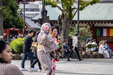 Tokyo, Japonya, 28 Ekim 2023: Renkli kimonolu kadınlar Senso-ji Tapınağında güneşli bir günün tadını çıkarıyor