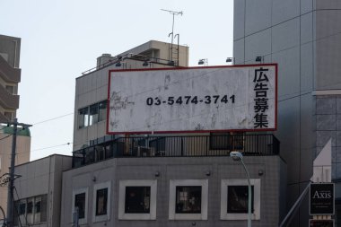 Tokyo, Japonya, 28 Ekim 2023: Bir binanın ön cephesinde yıpranmış ilan panosu
