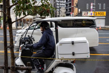 Tokyo, Japonya, 29 Ekim 2023: Şehir kavşağında elektrikli araç teslimat personeli
