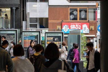 Tokyo, Japonya, 29 Ekim 2023: Kalabalık bir kentsel bölgedeki çeşitli dükkanların önünden geçen insanlar