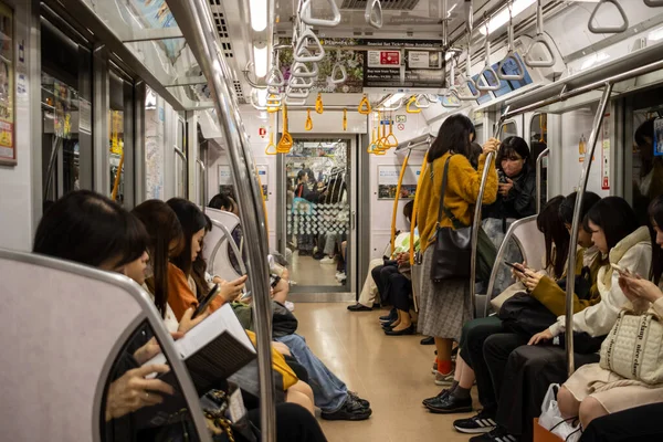 Tokyo, Japonya, 29 Ekim 2023: Metro treninde akıllı telefon kullanan banliyö sakinleri