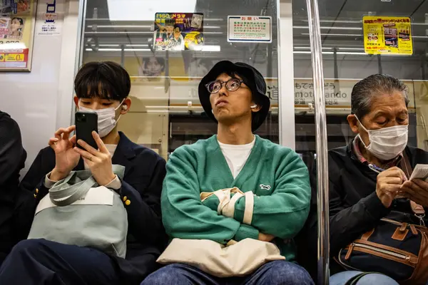 Tokyo, Japonya, 29 Ekim 2023: Metroda akıllı telefon kullanan banliyö sakinleri
