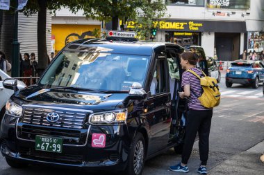 Tokyo, Japonya, 29 Ekim 2023: Yoğun bir Tokyo caddesinde taksi çeviren yolcular