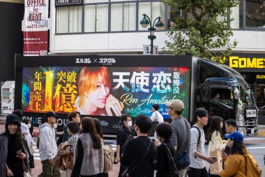 Tokyo, Japonya, 29 Ekim 2023: İnsanlar canlı grafiklerle bir reklam kamyonunun önünden geçiyor