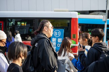 Tokyo, Japonya, 29 Ekim 2023: Şehir yansıması olan otobüsün yanında bekleyen yolcular