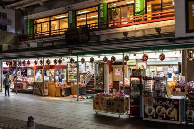 Tokyo, Japonya, 29 Ekim 2023: Dükkanlar ve geleneksel dekorasyonlarla dolu kalabalık bir Tokyo pazar caddesinde akşam