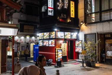 Tokyo, Japonya, 29 Ekim 2023: Geleneksel Japon restoranları ve tabelaları olan hareketli bir caddenin gece manzarası