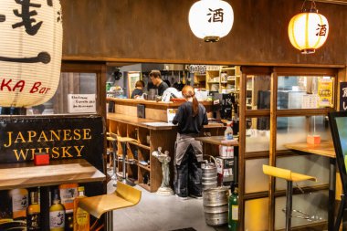 Tokyo, Japonya, 29 Ekim 2023: Geceleri müşterileri ve barmenleri olan bir Japon viski barının içi