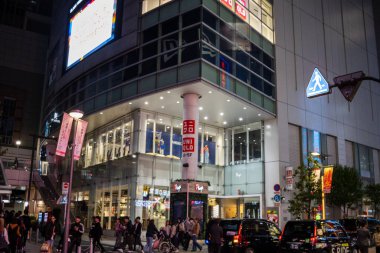 Tokyo, Japonya, 29 Ekim 2023: Tokyo 'daki UNIQLO bayrak gemisi mağazasının önünde akşam alışverişçileri