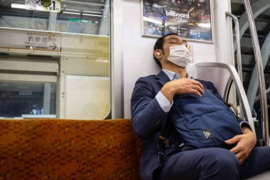 Tokyo, Japonya, 29 Ekim 2023: Tokyo Metroda Yüz Maskesiyle Uyuyan İş Adamı