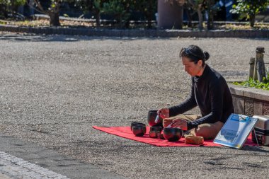 Tokyo, Japonya, 30 Ekim 2023: Tokyo parkında bir piknik sırasında çay hazırlayan kişi