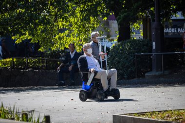 Tokyo, Japonya, 30 Ekim 2023: Yaşlı kişi parkta mobiletle geziyor