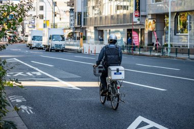 Tokyo, Japonya, 30 Ekim 2023: Şehir yolunda trafiği olan bir teslimatçı