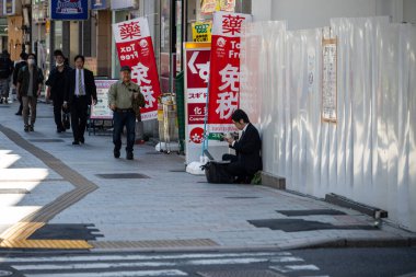 Tokyo, Japonya, 30 Ekim 2023: Kaldırımda Reklamların Yanında Oturan Adam