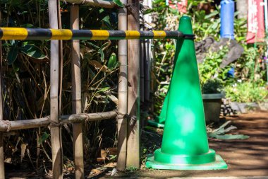 Tokyo, Japonya, 30 Ekim 2023: Tokyo caddesinde bambu çitlerinin yanındaki yeşil trafik konisi