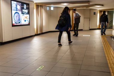 Tokyo, Japonya, 30 Ekim 2023: Dijital reklamlarla bir metro koridorunda yürüyen yolcular