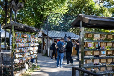 Tokyo, Japonya, 30 Ekim 2023: Shinto türbesindeki bir sergide renkli Ema plaklarını gezen ziyaretçiler