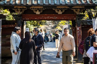 Tokyo, Japonya, 30 Ekim 2023: Geleneksel bir torii kapısından Shinto türbesine giren ziyaretçiler