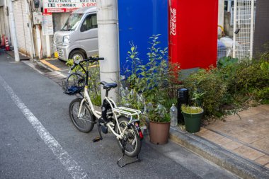 Tokyo, Japonya, 30 Ekim 2023: Bir binanın dışında saksı bitkileriyle park edilmiş bisiklet