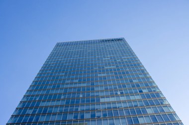 Tokyo, Japonya, 30 Ekim 2023: Açık mavi gökyüzüne karşı yüksek bir gökdelenin cam cephesi