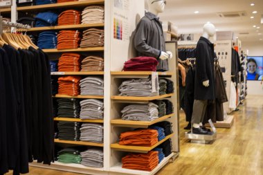 Tokyo, Japonya, 30 Ekim 2023: Katlanmış gömlek ve pantolon çeşitleri bir moda mağazasında sergileniyor