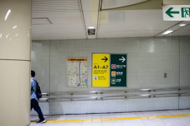 Tokyo, Japonya, 30 Ekim 2023: Tokyo metro koridorunda yön işaretleri ile yürüyen adam