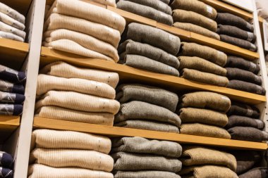 Tokyo, Japonya, 30 Ekim 2023: Bir moda mağazasında ahşap raflarda düzgünce dizilmiş kazaklar