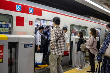Tokyo, Japonya, 30 Ekim 2023: Metro istasyonunda trene binmek için bekleyen banliyö sakinleri