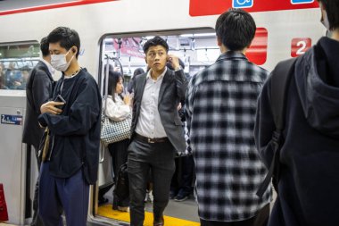 Tokyo, Japonya, 30 Ekim 2023: İş çıkış saatleri sırasında maskeli metro yolcuları