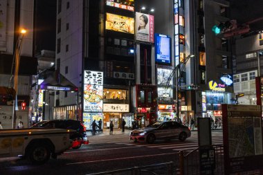 Tokyo, Japonya, 30 Ekim 2023: Tokyo 'da ışıklı reklam panoları ve arabaları olan yoğun bir caddenin gece görüntüsü