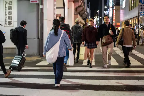 Tokyo, Japonya, 30 Ekim 2023: İnsanlar Tokyo 'nun hareketli kentlerinde geceleri karşıdan karşıya geçiyor