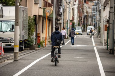 Tokyo, Japonya, 31 Ekim 2023: Sessiz bir Tokyo geçidinde gezinen bisikletçi