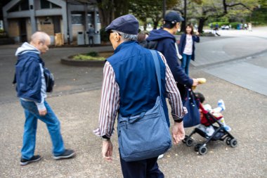 Tokyo, Japonya, 31 Ekim 2023: Yaşlı erkekler parkta yürüyüp sohbet ediyorlar