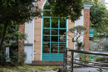 Tokyo, Japonya, 31 Ekim 2023: Büyük pencereli modern bir binanın yanındaki sessiz bahçe