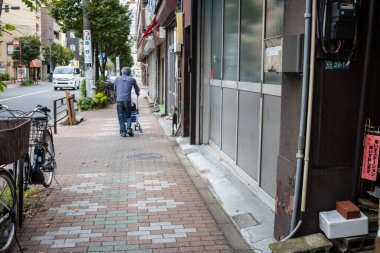 Tokyo, Japonya, 31 Ekim 2023: Tokyo kaldırımında bebek arabası süren adam