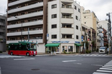 Tokyo, Japonya, 31 Ekim 2023: Tokyo caddesinde yerleşim binaları ile hareket halindeki kırmızı otobüs