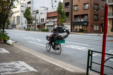 Tokyo, Japonya, 31 Ekim 2023: Şehir caddesinde bisikletli kurye