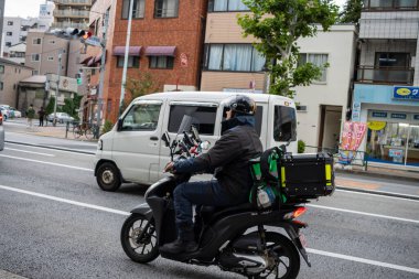 Tokyo, Japonya, 31 Ekim 2023: Yoğun bir Tokyo caddesinde motosiklet süren kurye