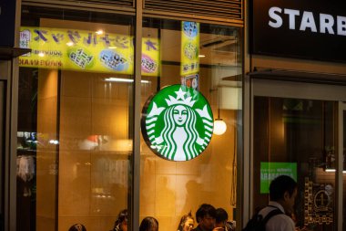 Tokyo, Japonya, 31 Ekim 2023: Starbucks kahve dükkanı gece aydınlandı ve müşterileri içerideydi
