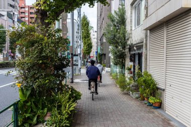 Tokyo, Japonya, 31 Ekim 2023: Huzurlu bir Tokyo yan sokağında bisiklet süren adam