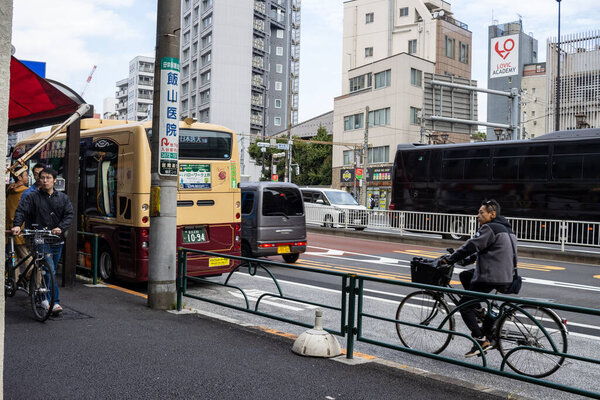 Tokyo, Japan, 31 October 2023: Busy street with a cyclist and buses in Tokyo's transportation scene