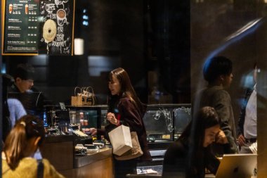 Tokyo, Japonya, 31 Ekim 2023: Müşteriler ve çalışanlar gece bir kahve dükkanında