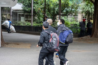 Tokyo, Japonya, 31 Ekim 2023: Sırt çantalı okul çocukları parkta yürüyor